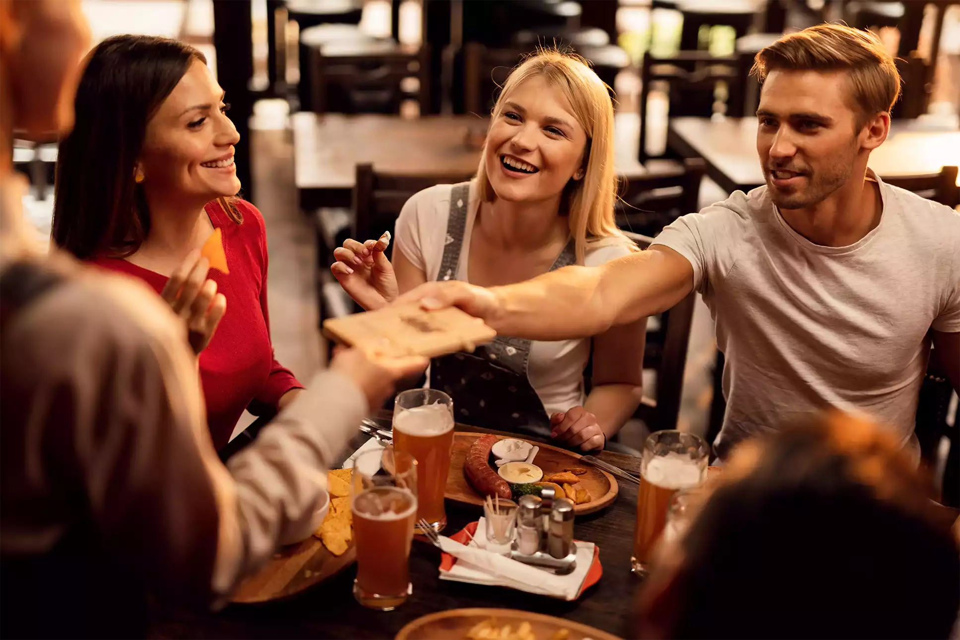 Amigos em uma mesa de jantar sorrindo enquanto comem.